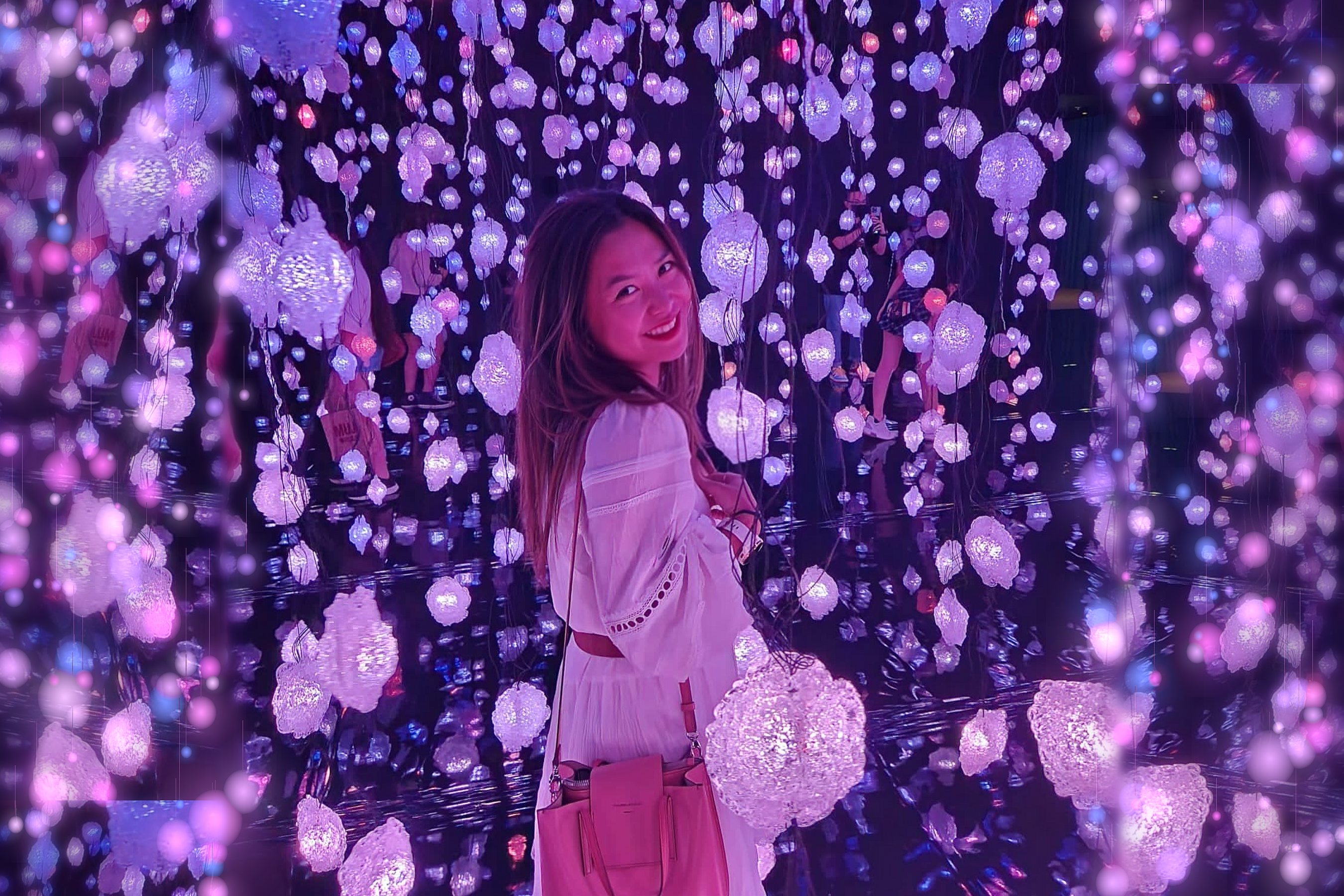 Shine smiling over her shoulder in a room of glowing pink and violet hanging lanterns